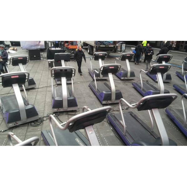 A row of tread machines in front of a building, showcasing new gym equipment.