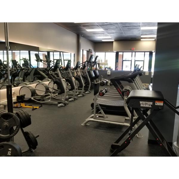 A gym offering a variety of tread machines and mirrors, featuring both new and remanufactured gym equipment.