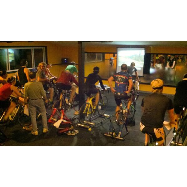 A group of people riding bikes in a room equipped with new gym equipment. A group of people riding bikes in a room equipped with new gym equipment.