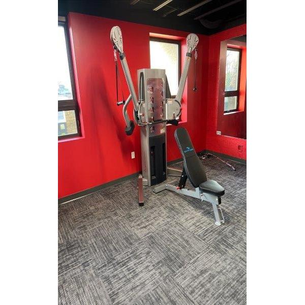 A gym room with red walls and a variety of new gym equipment.