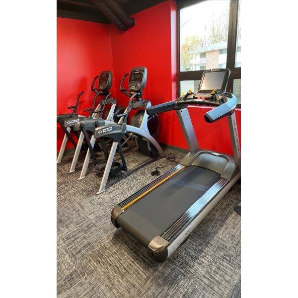 A gym room with new tread machines and remanufactured gym equipment, adorned with red walls.