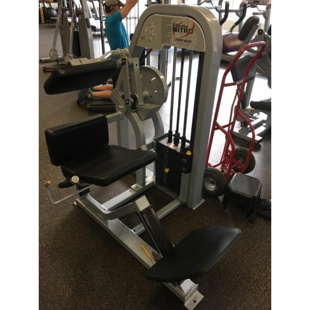 A person sitting on an exercise machine in a gym featuring remanufactured gym equipment.