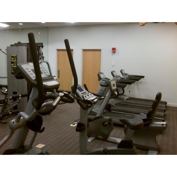 A gym room with several tread machines and mirrors, featuring new gym equipment.