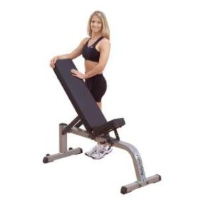 A woman gracefully perched on a 2" x 3" Body-Solid Flat / Incline Bench - New.