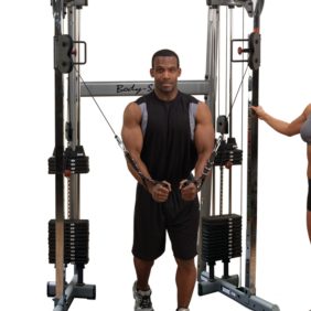 A man and woman standing next to a Body-Solid Functional Trainer 210- New.