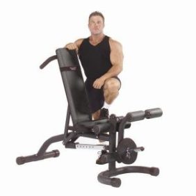 A man posing on a Body Solid Olympic Leverage Flat Incline Decline Bench - New surrounded by new gym equipment.