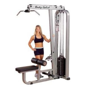 A woman confidently standing next to the Body Solid Selectorized Pro Clubline Lat Mid Row Machine 210 lbs Stack - New.