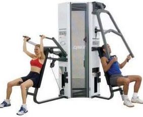 A man and a woman utilizing the Cybex Modular 4 Stack Jungle Gym - Serviced at the fitness center.