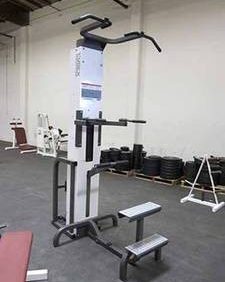 New and remanufactured Cybex Modular Assisted Chin Dip gym equipment in a room with other equipment.