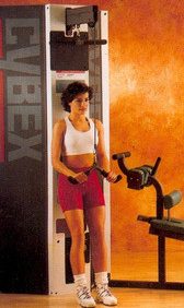 A woman is standing in front of a Cybex Modular Tricep Pushdown- Remanufactured.