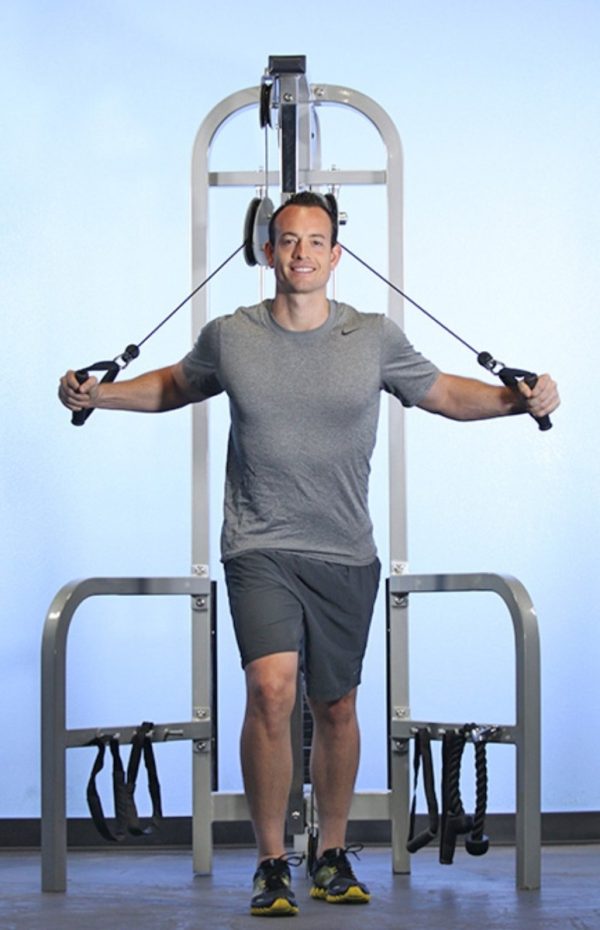 A man standing in front of a Muscle D Fitness High Low Pulley COMBO MACHINE.