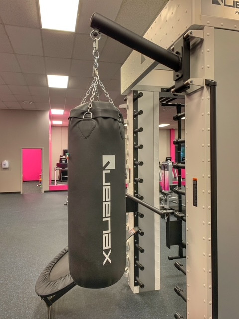 A gym with a Queenax Functional Training System - As Is Functional, offering new & remanufactured gym equipment and a wall-mounted punching bag.