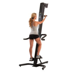 A woman is standing on a VersaClimber CM - New.