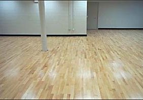 A room with white walls and Wood Flex Flooring, featuring new gym equipment.