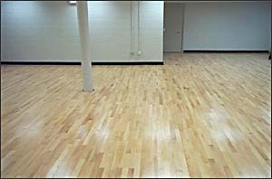 A room with white walls and Wood Flex Flooring, featuring new gym equipment.