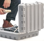 A man sitting on a gray case filled with new money. A man sitting on a gray case filled with new money.