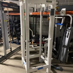 A gym with a squat rack and other equipment including the Technogym 4 Stack - As Is Functional.