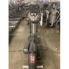 In a gym setting, a row of elliptical machines lines the floor, with focus on one labeled "626," known as the Cybex 626 Arc Trainer - As Is Functional.