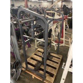 A Cybex VR2 Back Extension - Remanufactured sits on a wooden pallet, surrounded by other gym equipment in a bustling warehouse setting.