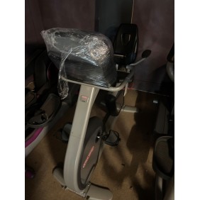 A Star Trac E-RB Recumbent Bike - Serviced, shrouded in protective plastic wrap, rests elegantly on a carpeted surface indoors.