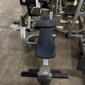 In a gym, the Life Fitness Signature Chest - As Is Functional, in blue and gray, is displayed on the concrete floor, offering ideal support for functional leg exercises.