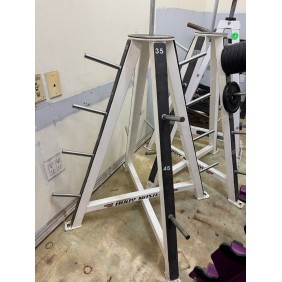 A Body Core Incline Bench - As Is Functional serves as a metal weight plate rack with multiple pegs, loaded with plates for easy access, enhancing efficient workouts and core strengthening in a gym.