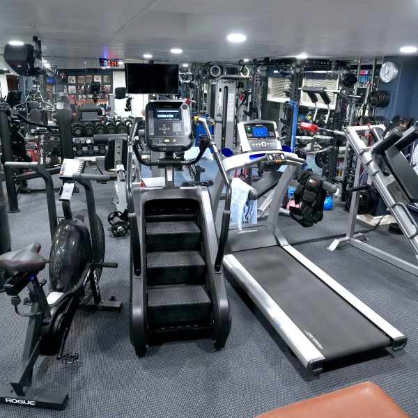 A fully equipped home gym in St. Louis, featuring a variety of exercise machines like treadmills, bikes, and free weights. The walls are adorned with sports memorabilia, creating the perfect fitness center vibe.