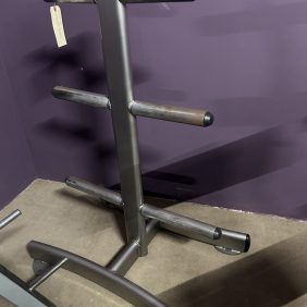 The Body Solid 3-Tier Dumbbell Rack - Remanufactured features multiple horizontal bars and stands prominently against a purple wall, its sleek design beautifully complemented by the carpeted floor—ideal for organizing your Body Solid equipment collection.