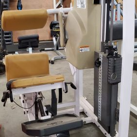 Leg extension machine with tan seat and backrest, weight stack on the right, and adjustable lever for exercise settings.
