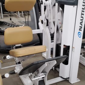 Nautilus lower back exercise machine with padded seats and handles in a gym setting.