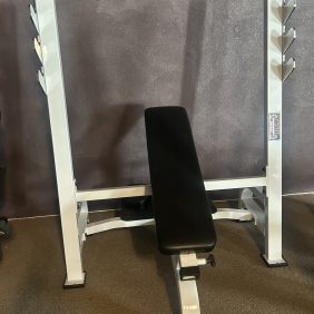 A serviced gym features a Hoist Olympic Decline Bench, which targets lower chest muscles effectively, alongside an adjustable weight bench and barbell rack for effortless workouts.