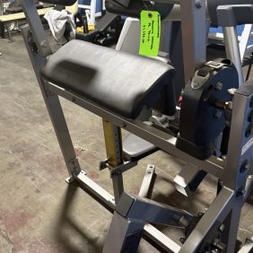 The Hammer Strength Plate Loaded Tricep is a seated gym machine with padded back support and adjustable features, designed for tricep workouts, and is placed on a concrete floor in an indoor facility.