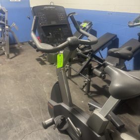 Life Fitness Upright Bike - Serviced, featuring a digital display and green tag, fully serviced and set among other gym equipment with wall warning signs.